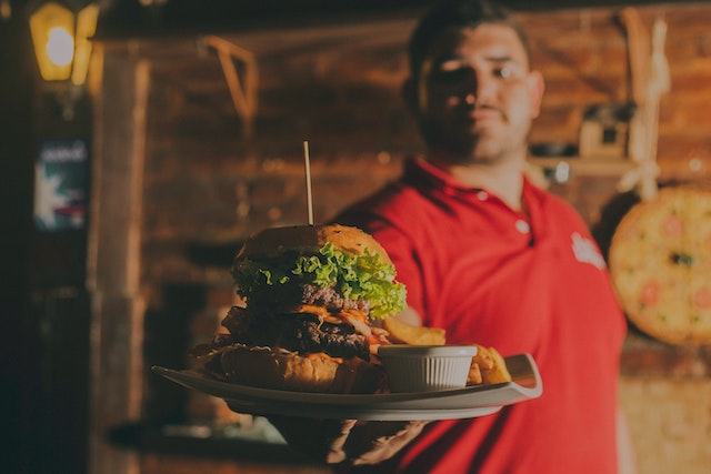 Guy holds plate with burger